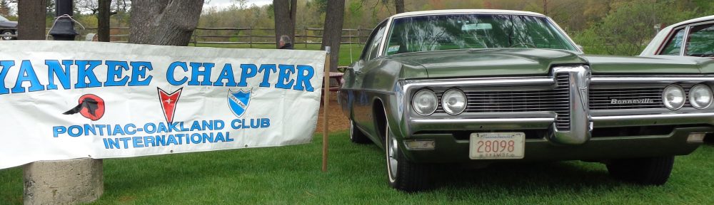 Vintage silver car parked on grass near a sign for a car club.